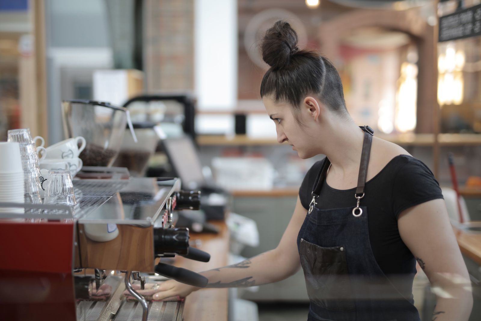 A barista working the espresso machine at a cafe counter