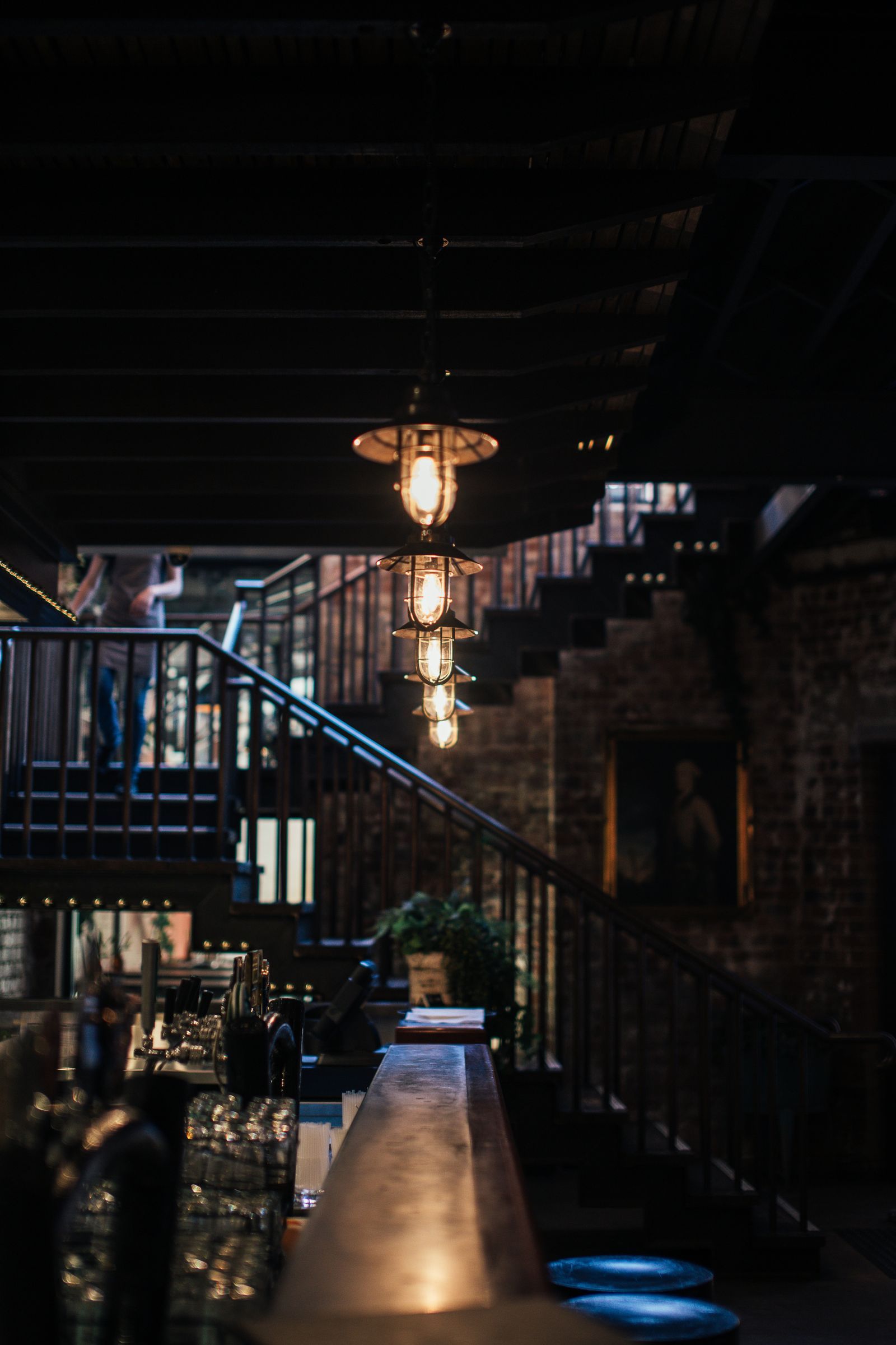 A warm-lit bar and staircase in a second venue at the end of service