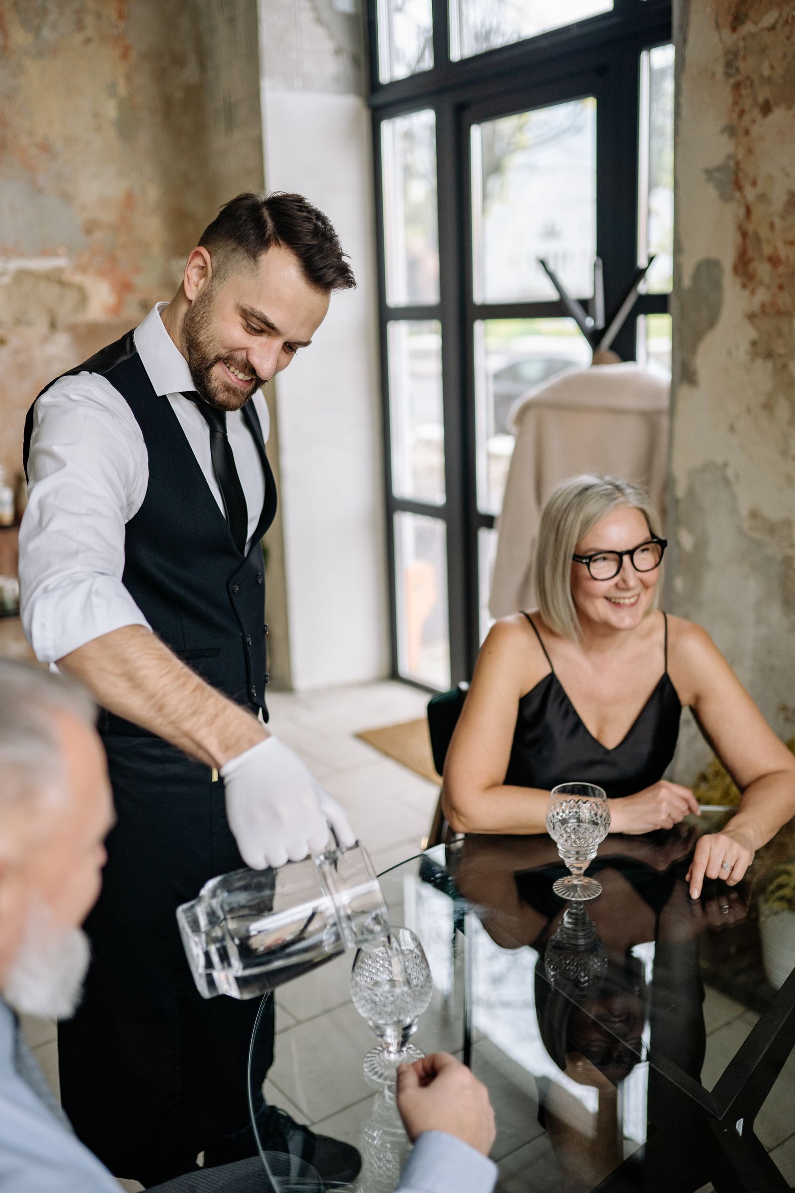 A waiter pouring for a seated guest during evening service